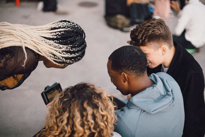 High angle view of multi-ethnic friends watching movie on smart phone at skateboard park