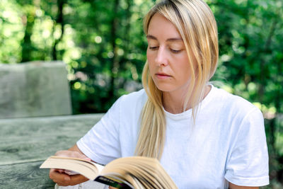 A young woman reads a book outdoors.