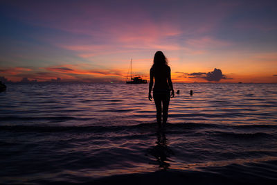 Silhouette woman standing at beach during sunset