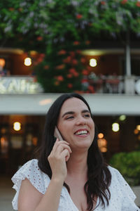 Candid portrait of happy young woman talking on the phone in city