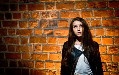 Portrait of young woman standing on wall