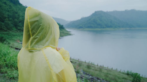 Rear view of woman standing against lake