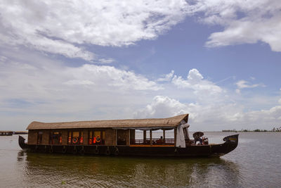 Passenger boat on sea against cloudy sky