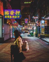 Rear view of woman walking on illuminated road