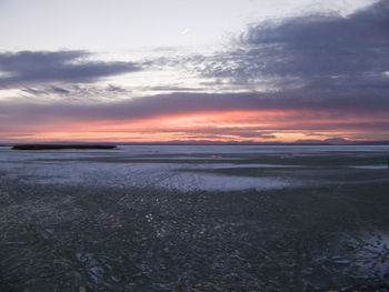 Scenic view of sea against cloudy sky at sunset