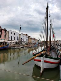 Fishing boat moored at harbor against sky