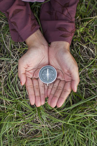 Close-up of woman holding navigational compass on field