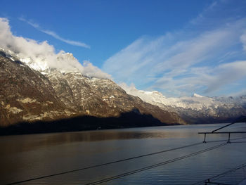 Scenic view of lake by snowcapped mountains against sky