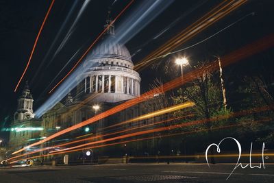 Light trails on street against buildings at night