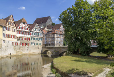 Arch bridge over river by buildings against sky