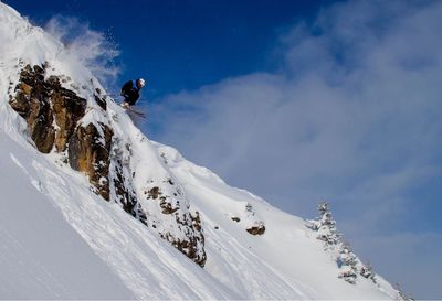 Low angle view of person skiing on snowcapped mountain against sky