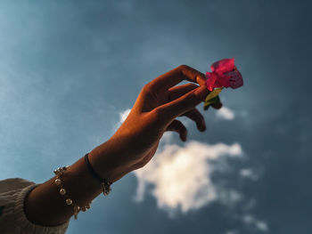 Cropped hand of woman holding heart shape against sky