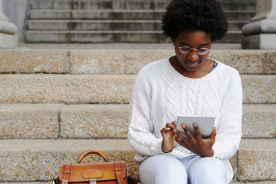 Midsection of man using mobile phone while sitting on staircase