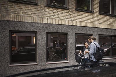 Friends with bicycles reflecting in window at city