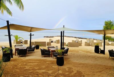 Chairs and tables on beach against sky