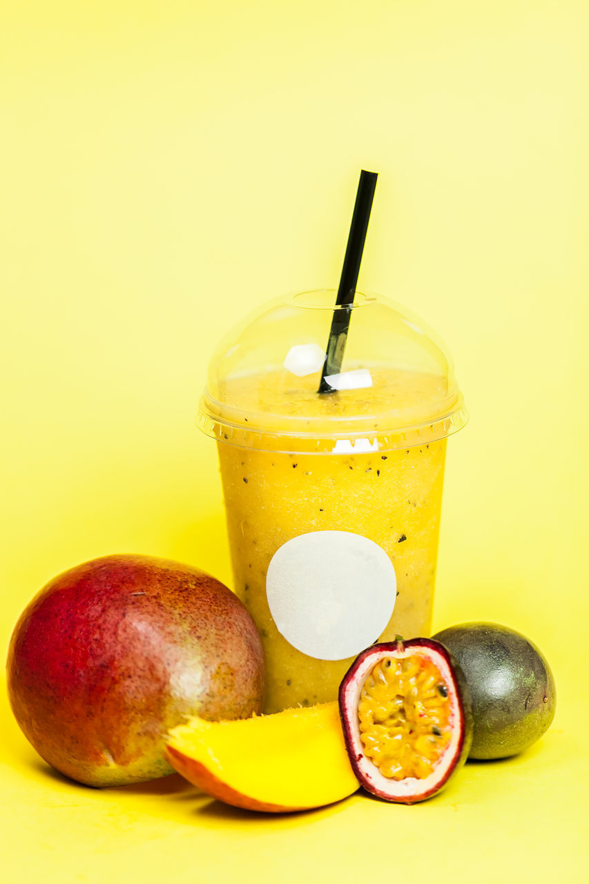 CLOSE-UP OF YELLOW AND DRINK AGAINST ORANGE BACKGROUND