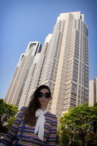 Low angle portrait of smiling young woman standing in city
