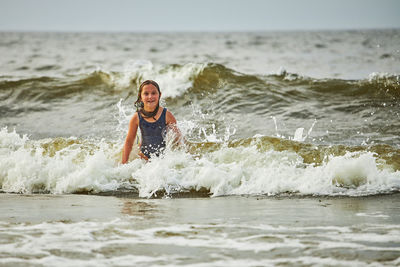 Little girl playing with waves in the sea. kid playfully splashing with waves. child jumping in sea