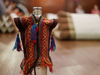 A bottle of water in a bottle holder in colorful hilltribe shirt with background of khantok dinner