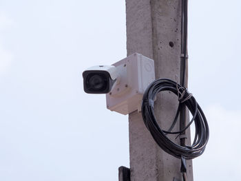 Low angle view of security camera against sky