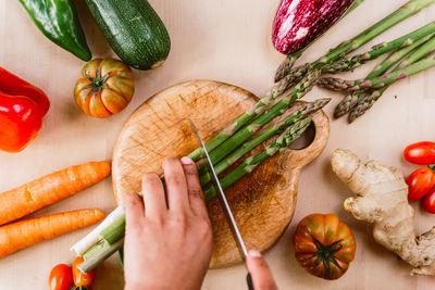 High angle view of hand holding vegetables on cutting board