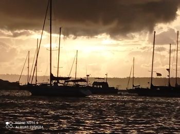 Sailboats in sea at sunset