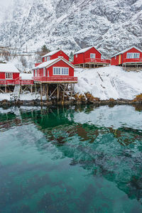 Houses by lake against snowcapped mountains during winter