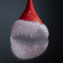 Close-up of water balloon bursting against black background with reflection