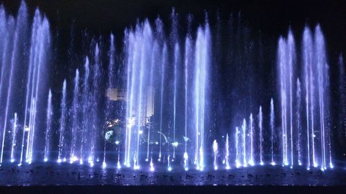 Low angle view of illuminated fountain against sky at night