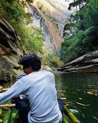 Rear view of man standing on rock by river