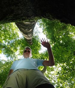 Low angle view of man sitting by tree