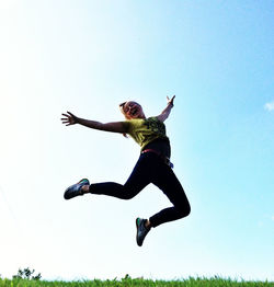 Low angle view of man jumping against sky