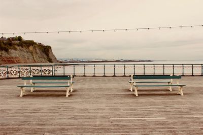 Empty bench against sea against sky