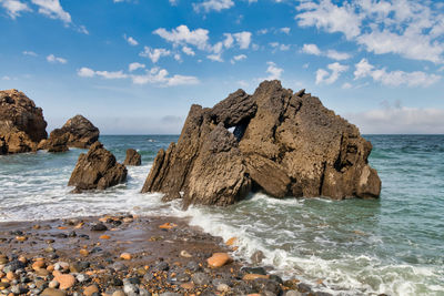 Scenic view of rocks on beach against sky