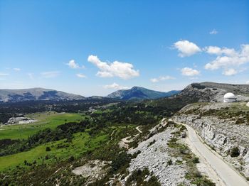 Scenic view of road by mountains against sky