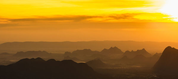 Scenic view of silhouette mountains against orange sky