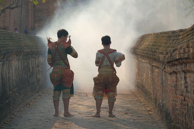 Rear view of men wearing traditional clothing standing on footpath