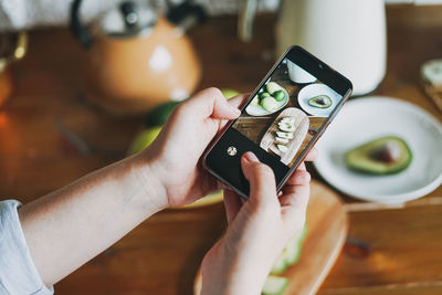 Midsection of person holding mobile phone on table