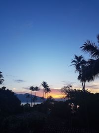 Silhouette palm trees against sky during sunset