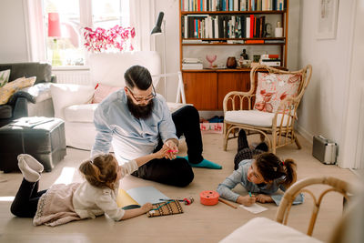 Father playing with daughters in living room at home