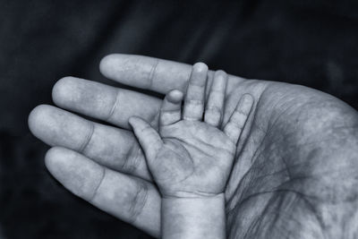 Close-up of father holding baby hand