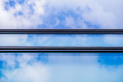 Low angle view of reflection of sky on glass window