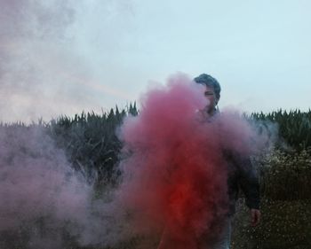 Man standing amidst red smoke