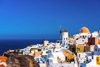 Townscape by sea against clear blue sky