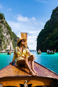 Woman sitting on boat in sea against sky