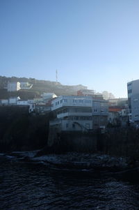 Buildings by sea against clear sky