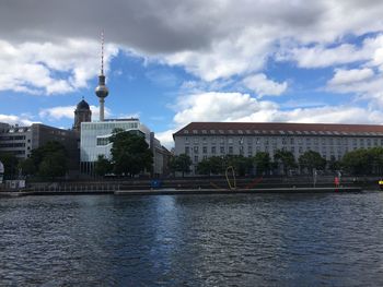 City at waterfront against cloudy sky