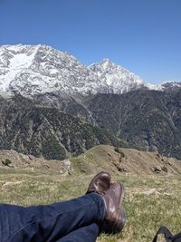 Man relaxing on mountain against blue sky