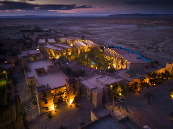 High angle view of illuminated buildings by sea against sky at dusk