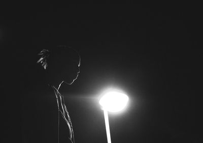 Low angle view of illuminated lighting equipment against black background